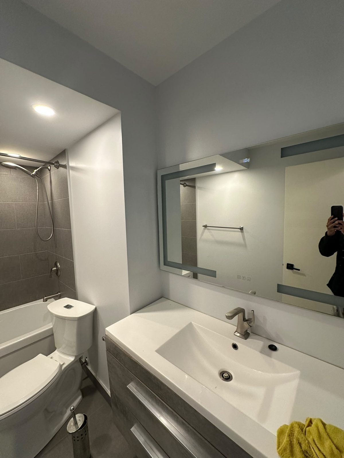 Renovated bathroom with a white floating vanity, backlit LED mirror and grey floor tile in a Toronto-area condo