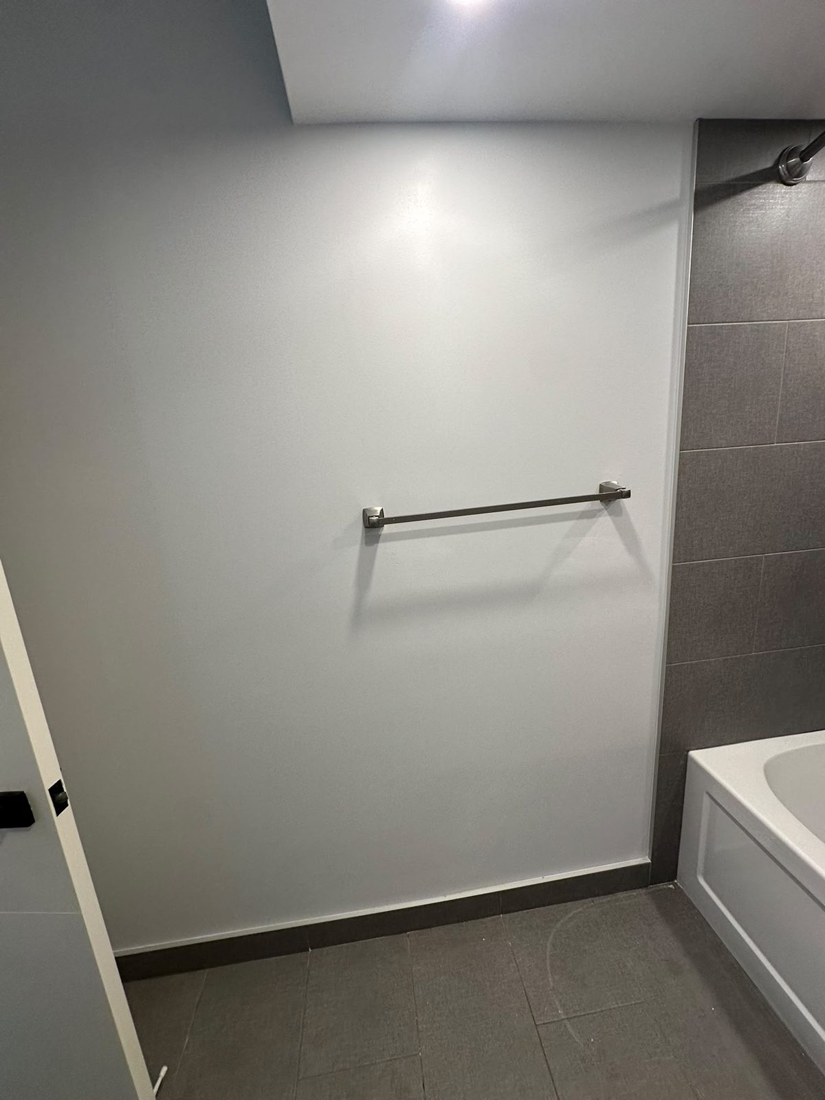Repainted bathroom wall with the towel bar reinstalled after drywall repair, Toronto-area bathroom
