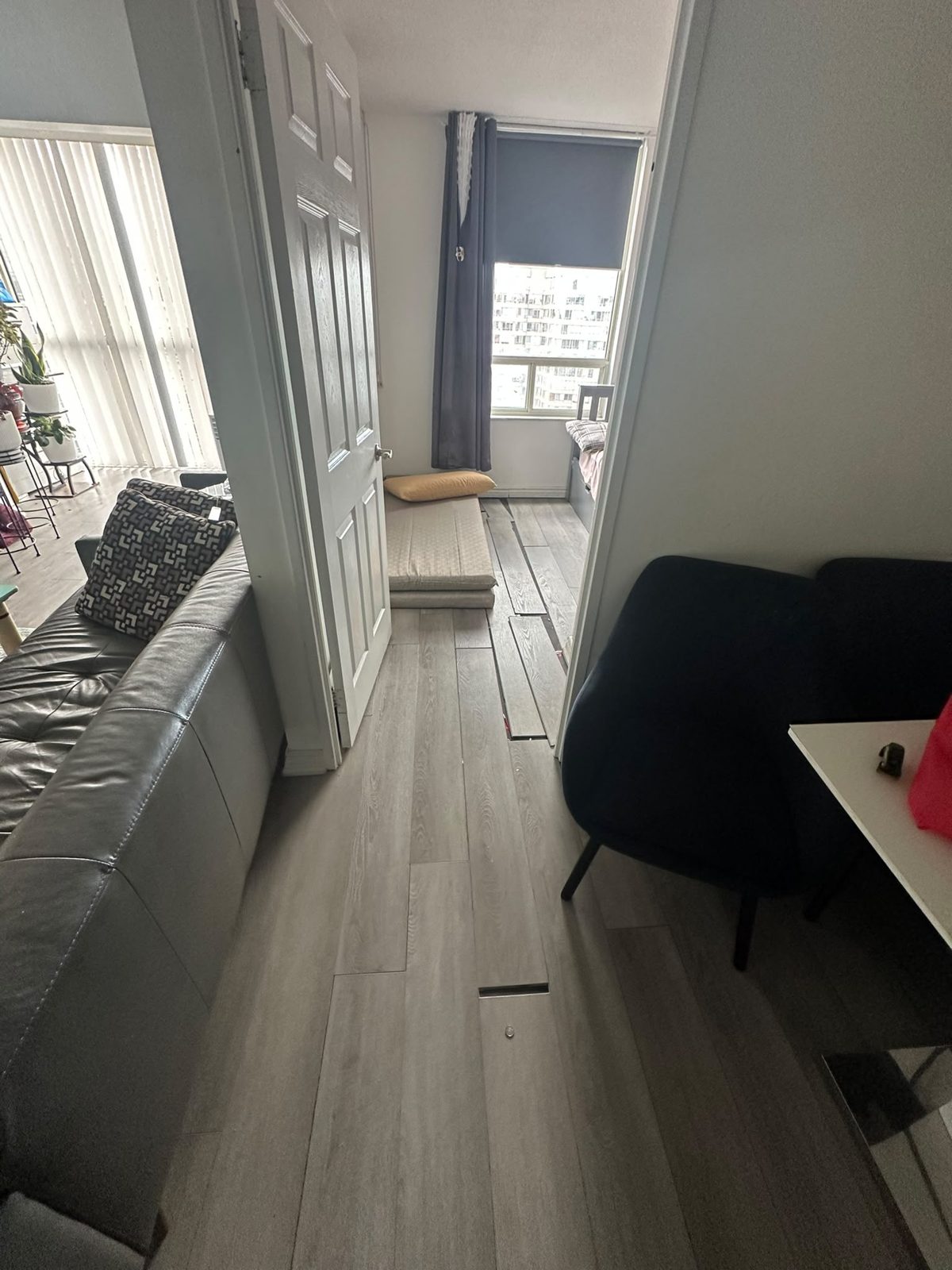 Condo living area with new grey plank flooring installed room by room around the furniture, Toronto flooring renovation
