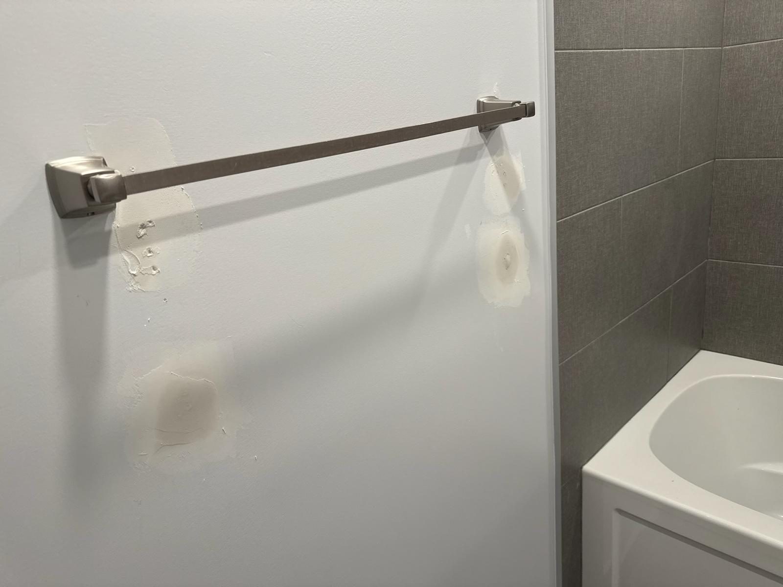 Patched and sanded drywall behind a towel bar before painting, bathroom wall repair in the Toronto area