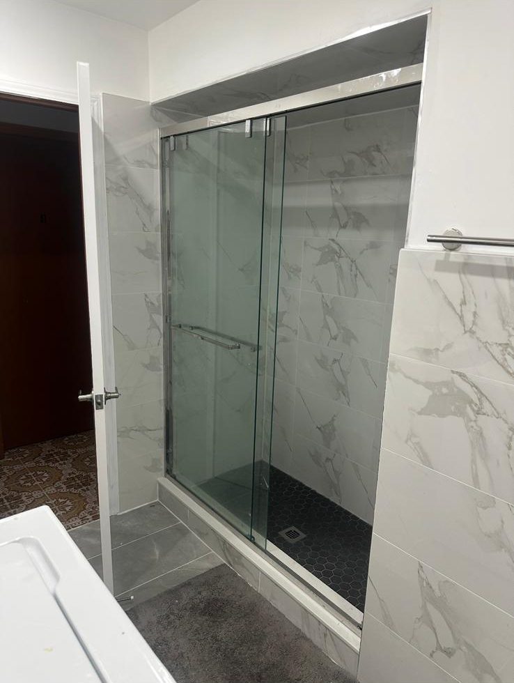 Sliding glass shower door on a marble-look porcelain tile shower in a completed Toronto-area condo bathroom renovation