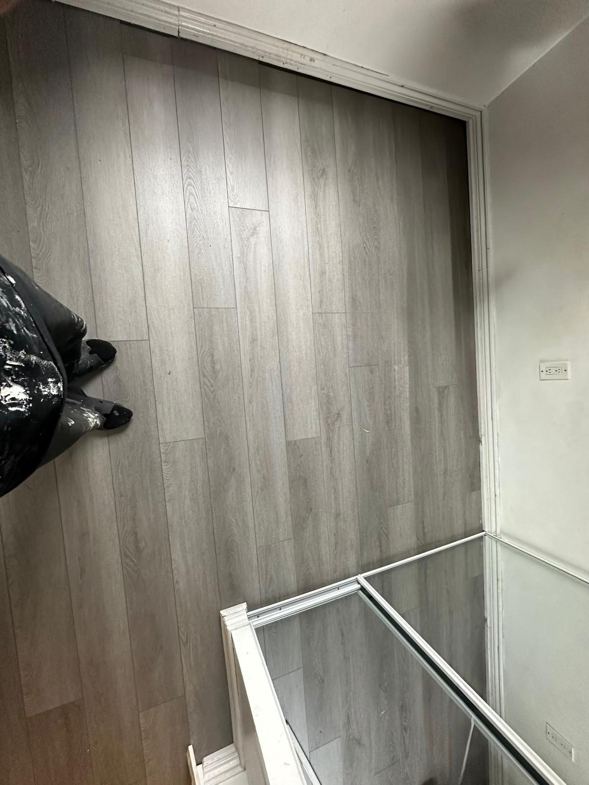 Grey vinyl plank flooring installed up to a glass stair railing in a GTA home
