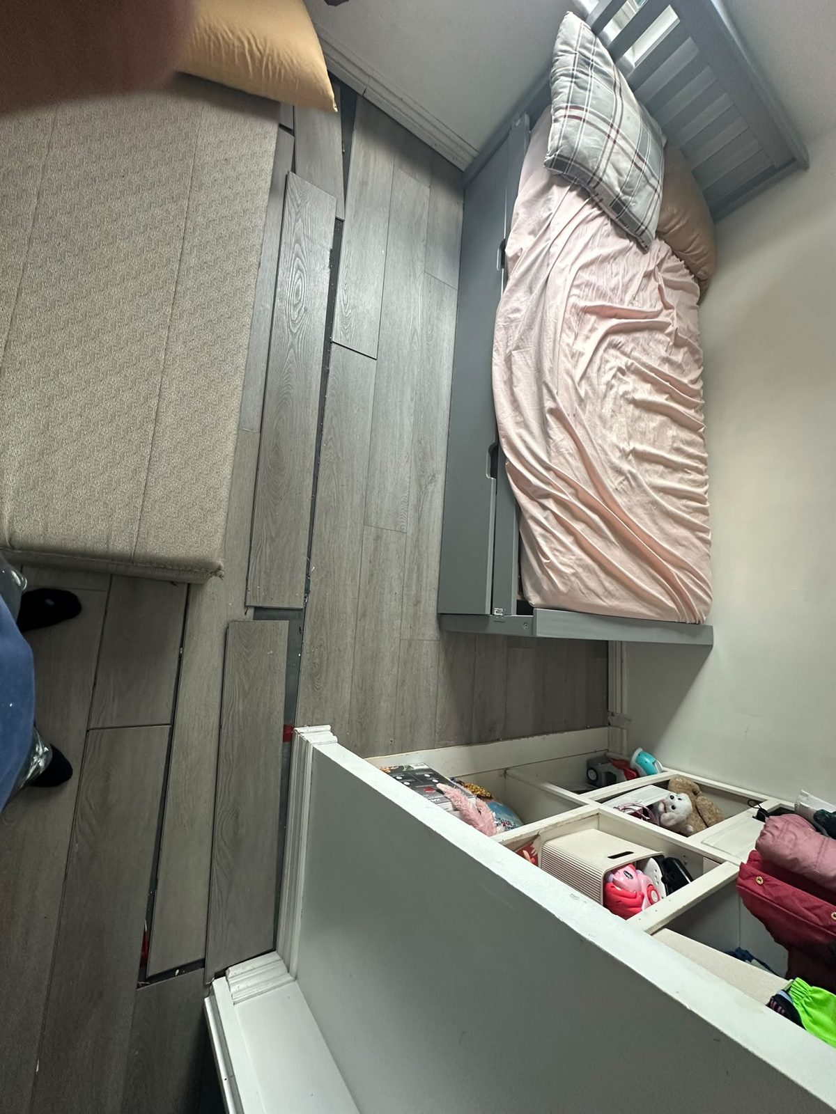 Grey laminate flooring being installed in a bedroom with planks staged beside the bed frame, GTA