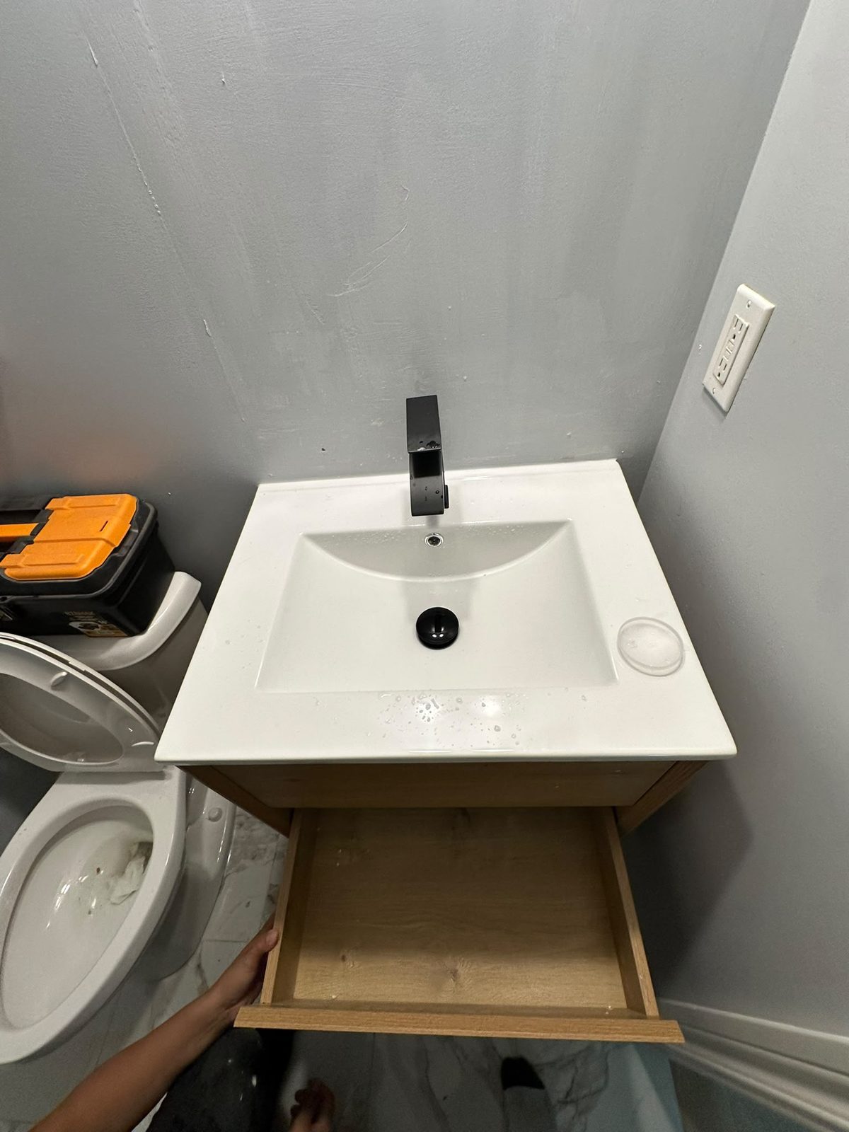 Wall-mounted wood vanity with a white integrated sink and matte black faucet installed by Fix N Clean in a Toronto bathroom
